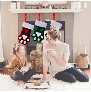 Detailed view of three plaid cat paw Christmas stockings hanging by a cozy fireplace