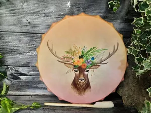 Detail of shamanic hand drum with deer and floral illustration on dark wood