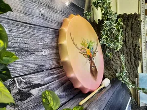 Close-up of hand-painted shaman drum featuring a floral deer head and wooden mallet