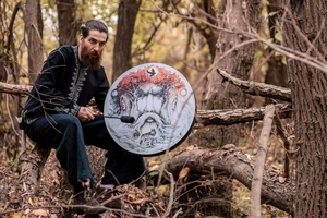Macro detail of shaman drum featuring the Tree of Life and wolf illustration in a forest