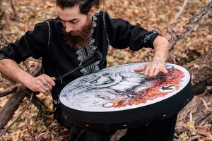 Outdoor scene of a shamanic drum with Tree of Life art and a black drumstick