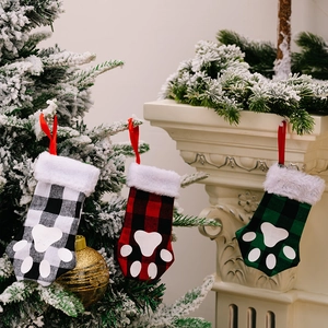 Three-piece buffalo plaid Christmas pet paw stockings hanging by fireplace for holiday decor