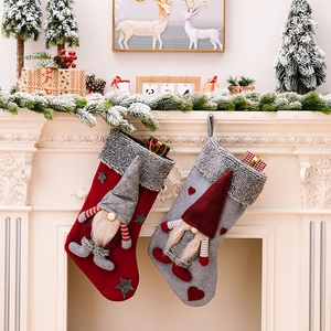 Detail of red and grey Christmas stockings with plush trim and gnome hanging on a white mantel
