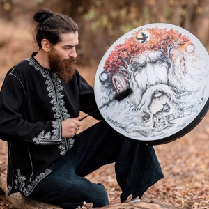 Handheld shamanic frame drum with Tree of Life and wolf totem art being played outdoors