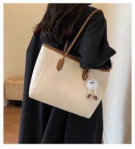 Detail of cream large tote bag with brown handles and a cute plush charm accessory