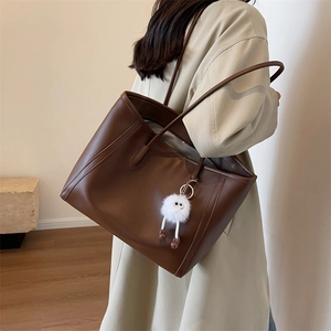 Deep brown faux leather tote bag detail with cute white plush monster charm