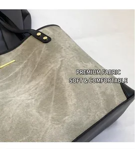 Detail of soft grey suede tote bag featuring black leather trim and golden hardware