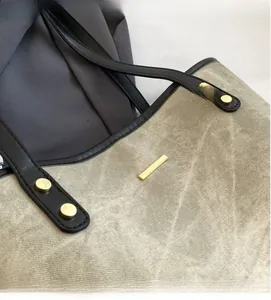 Detail of canvas tote bag featuring premium golden metal hardware and black leather strap
