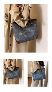 Detail of blue textured tote bag with brown leather trim and golden metal hardware