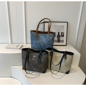 Three textured leather tote bags in blue, taupe, and beige on tiered minimalist display