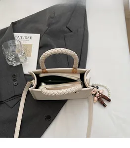 Detail view of cream white crossbody bag with braided rope handles and zip compartment
