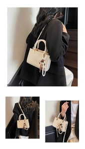 Detail of cream crossbody bag featuring woven handle, pearl chain, and cute doll pendant