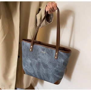 Detail of grey marble texture fabric tote bag with brown leather handles and gold trim