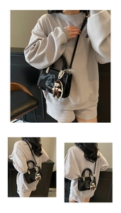 Detail of black patent leather crossbody bag with pearl charm and woven handle