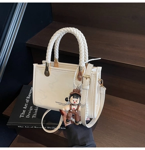 Detail of cream white crossbody bag featuring woven handle and luxury leather texture