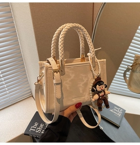 Detail of cream leather crossbody bag with woven handle and cute pearl chain charm
