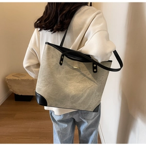 Detail of grey-green stone textured tote bag showing high-quality leather and metal plate