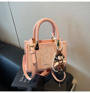 Detailed macro view of pink marble texture PU leather bag with woven handle and charm