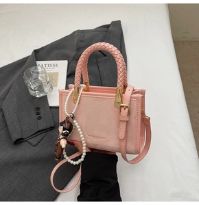 Pink glossy leather square bag with woven handle, gold hardware and pearl charm detail
