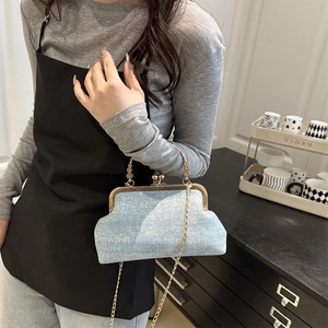 Light blue vintage clasp purse with gold metal handle and chain, shown by a model