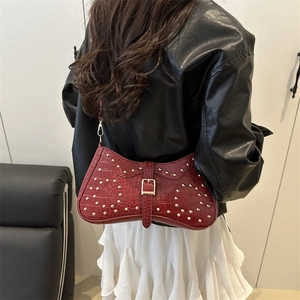 Burgundy faux crocodile baguette bag with gold studs shown on a model's shoulder