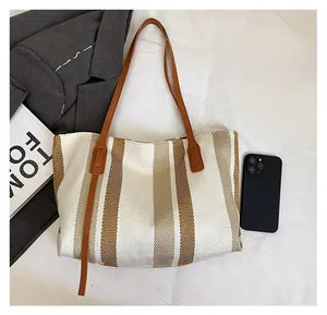 Detail view of large striped woven tote bag with leather straps and size comparison
