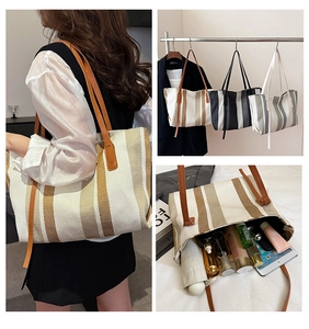 Detail view of large striped canvas tote bag with brown faux leather straps in three colors