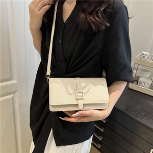 Chic cream leather crossbody bag with square buckle decoration worn by model