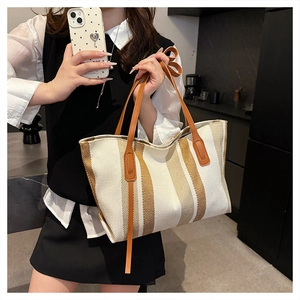 Detail of striped canvas tote bag showing large capacity and brown leather handles