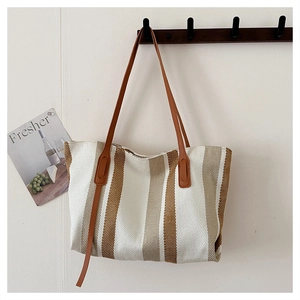 Close-up of the textured vertical stripe fabric and durable leather handles of the tote bag