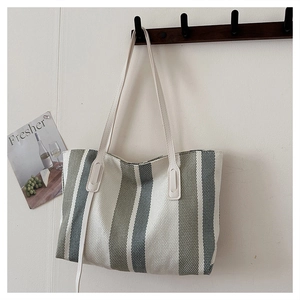 Detailed texture of forest green striped canvas tote bag hanging on wooden rack