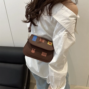 Brown casual messenger bag with cartoon patches and adjustable strap on female model