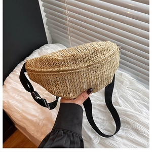 Detail of hand-woven straw waist bag with adjustable black strap and zipper closure