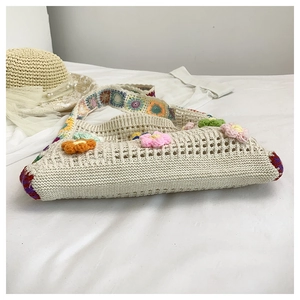 Detailed close-up of a handmade crochet tote bag featuring 3D floral accents and wide straps