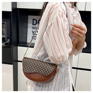 Detail of saddle bag with vintage geometric pattern and wavy flap edge on brown leather