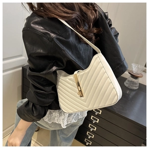 Détail d'un sac à main blanc matelassé avec surpiqûres en V et boucle dorée sur le mannequin