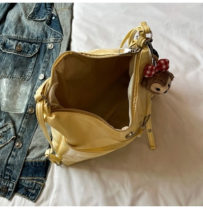 Top view of bright yellow large tote bag with zipper closure and bear charm on bed
