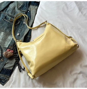 Detail of glossy pale yellow leather tote bag featuring a cute plush bear charm accessory