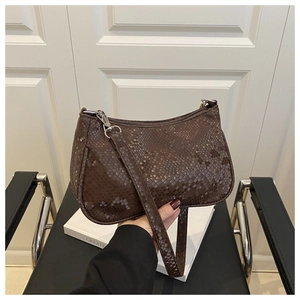 Détail d'un sac baguette en cuir synthétique marron foncé avec fermeture éclair argentée