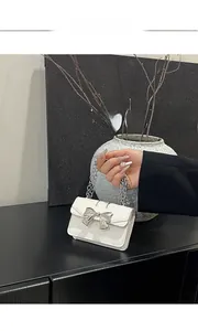 Detailed close-up of the silver metal bow clasp and chain on a mini off-white handbag