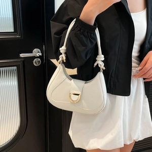 White minimalist saddle bag with gold horseshoe buckle and knotted strap on model