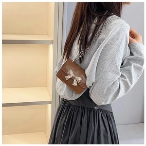 Detail of vintage brown mini crossbody bag with silver bow accent and chain strap