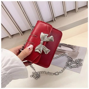 Detailed shot of red mini chain bag featuring a silver metal bow and flap closure