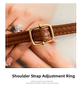 Detailed close-up of brown leather shoulder strap with gold metal adjustment buckle