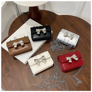 Multiple colors of mini crossbody square bags with oversized silver metal bow clasps