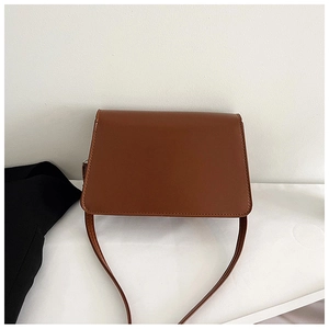 Top view of brown leather shoulder bag with flap closure on minimalist white background