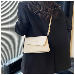 Detail of crossbody bag featuring cream leather flap and light woven texture body