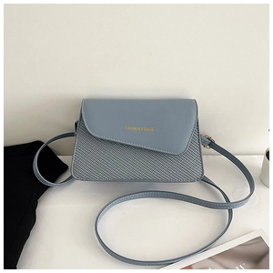 Detail of blue square crossbody bag featuring asymmetric flap and woven texture contrast