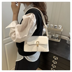 Detailed side view of white crocodile pattern shoulder bag with golden lock on a model