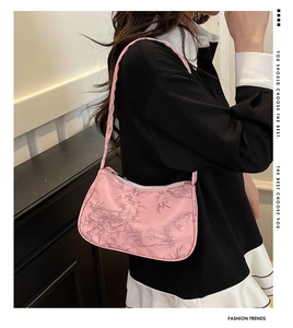 Close-up of pink baguette bag with bamboo pattern on a model’s shoulder in a stylish setting